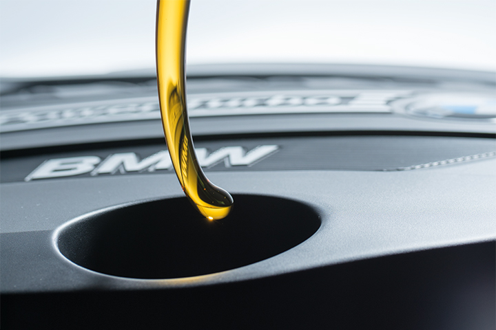 Original BMW Engine Oil pours into BMW vehicle engine. 