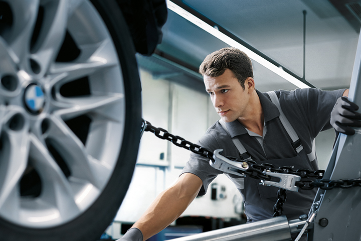 A technician in a Collision Repair Facility positioning a BMW for bodywork