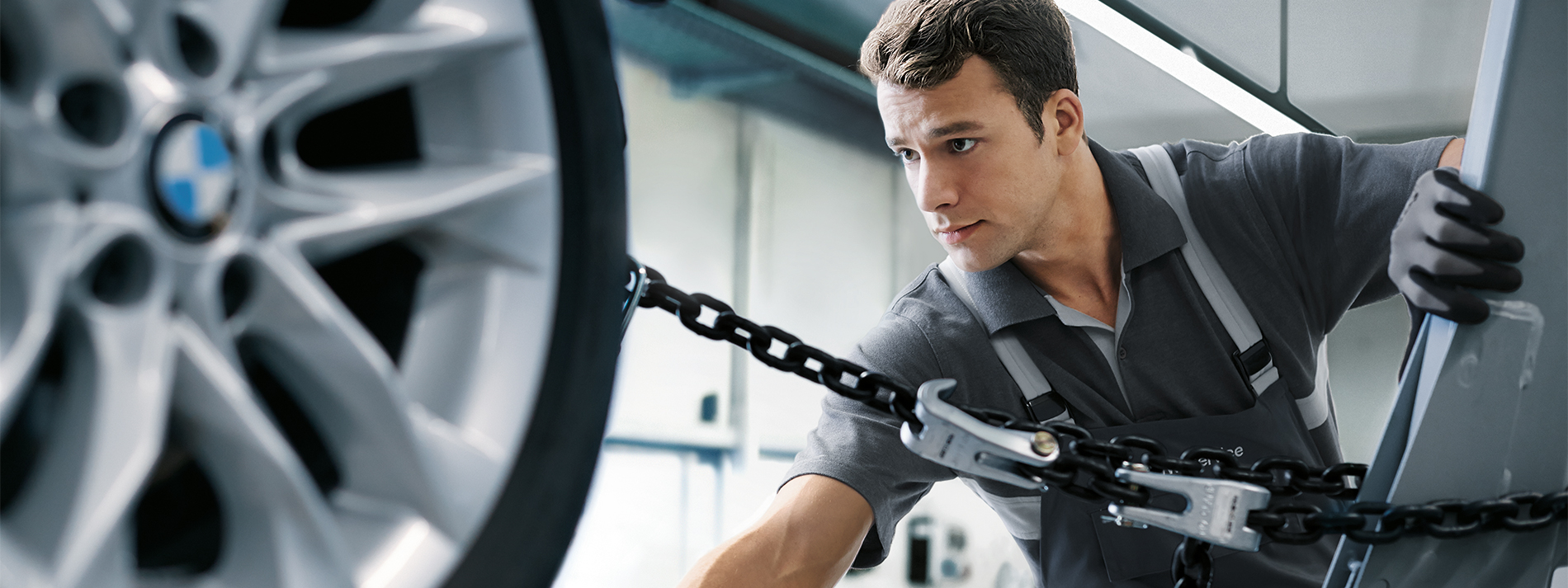 A technician in a Collision Repair Facility positioning a BMW for bodywork
